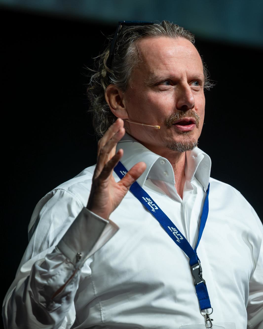 Andy Fitze spricht gestikulierend auf einer Konferenzbühne.