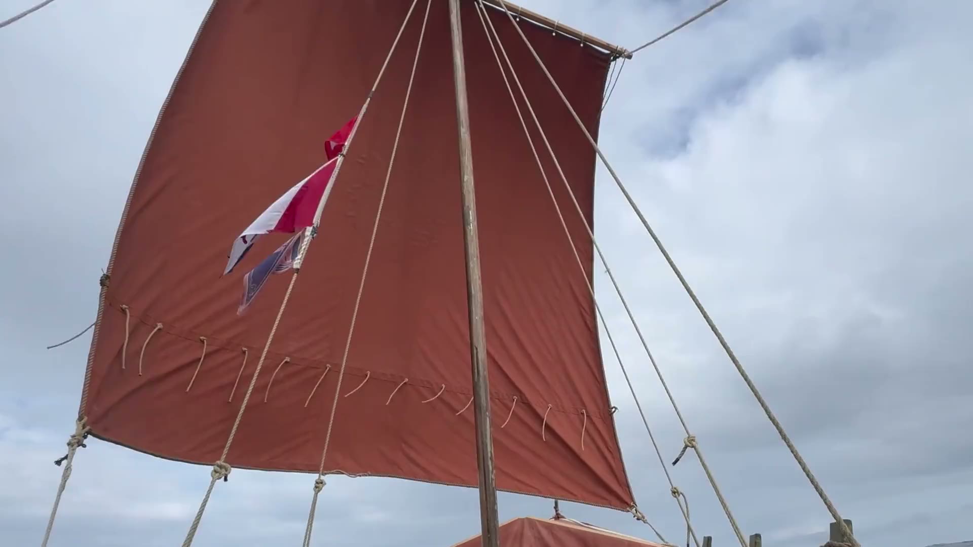 Rotes Rahsegel im Wind über offener See, vom Boot aus gefilmt